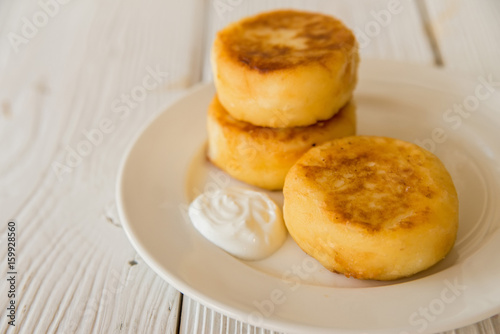 Cottage cheese cakes on plate with sour cream
