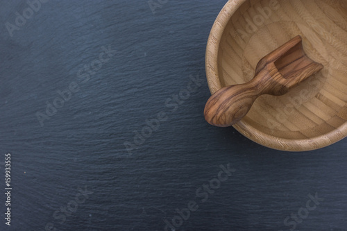 Olive wood scoop and wooden bowl on black background of slate or stone