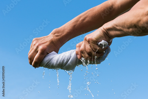 Hands squeeze wet cloth.