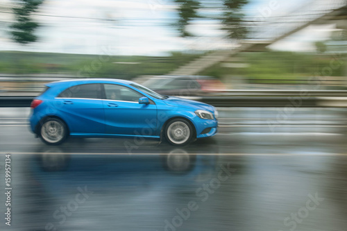 blue car driven on rainy roads with blur background © Leonart's