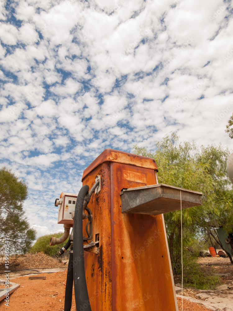 Rusty old australian diesel fuel pump in a sun drenched arid landscape. A rusty fuel pump against the vibrant famous orange sand and vibrant blue sky in the western australian desert. Rusty old australian diesel fuel pump in a sun drenched arid landscape. A rusty fuel pump against the vibrant famous orange sand and vibrant blue sky in the western australian desert.