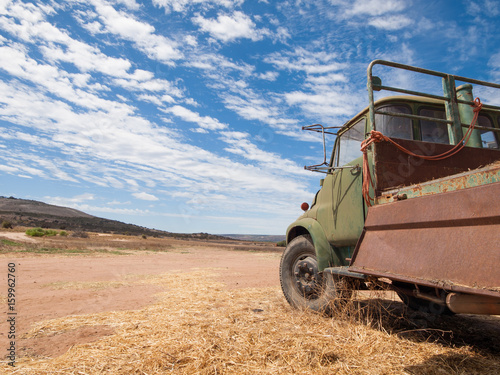 Rusty old australian cattle truck in a sun drenched arid landscape. A rusty cattle van against the vibrant famous orange sand and vibrant blue sky in the western australian desert.