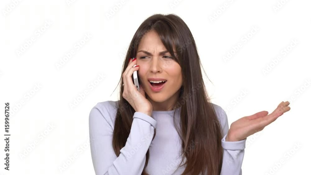 Concerned Caucasian female with brunette hair speaking through smartphone with boyfriend and arguing over white background Concerned Caucasian female with brunette hair speaking through smartphone with boyfriend and arguing over white background