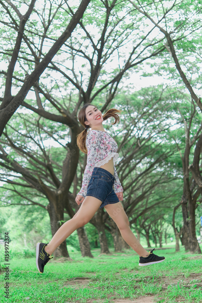Happy Young Woman Jumping with beautiful smile at tunnel tree bright tone,preety girl fun outdoor Happy Young Woman Jumping with beautiful smile at tunnel tree bright tone,preety girl fun outdoor