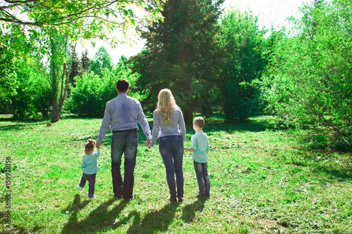 A family of four walks in the park. © ferkhova