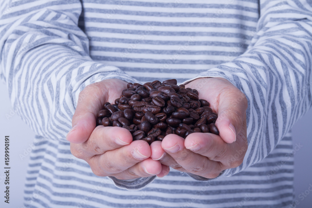 Coffee beans in female hands in white long sleeve shirt Coffee beans in female hands in white long sleeve shirt