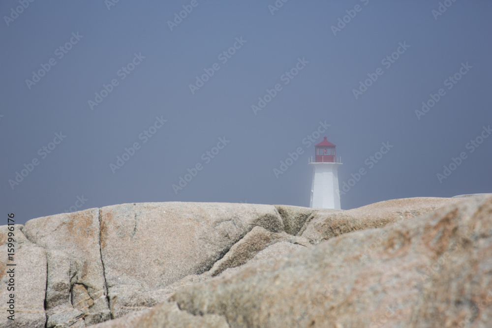 Peggy's Cove on a foggy day with the lighthouse in the distance 