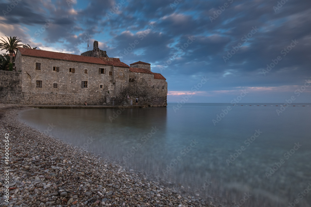 Ancient town on the edge of the sea with blurred water surface and colorful dramatic sky at sunset
