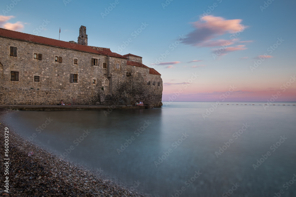 Ancient town on the edge of the sea with blurred water surface and colorful gradient sky at sunset