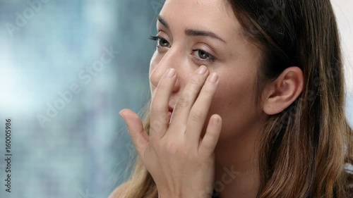 Young attractive woman puts eye cream on her face