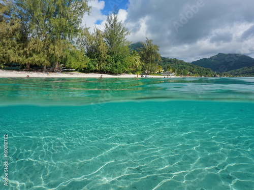 Over and under sea surface near tropical beach shore with a sandy seabed underwater, Fare, Huahine island, Pacific ocean, French Polynesia