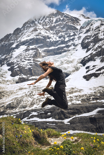 Happy girl jumping, beautiful landscape in Swiss Alps