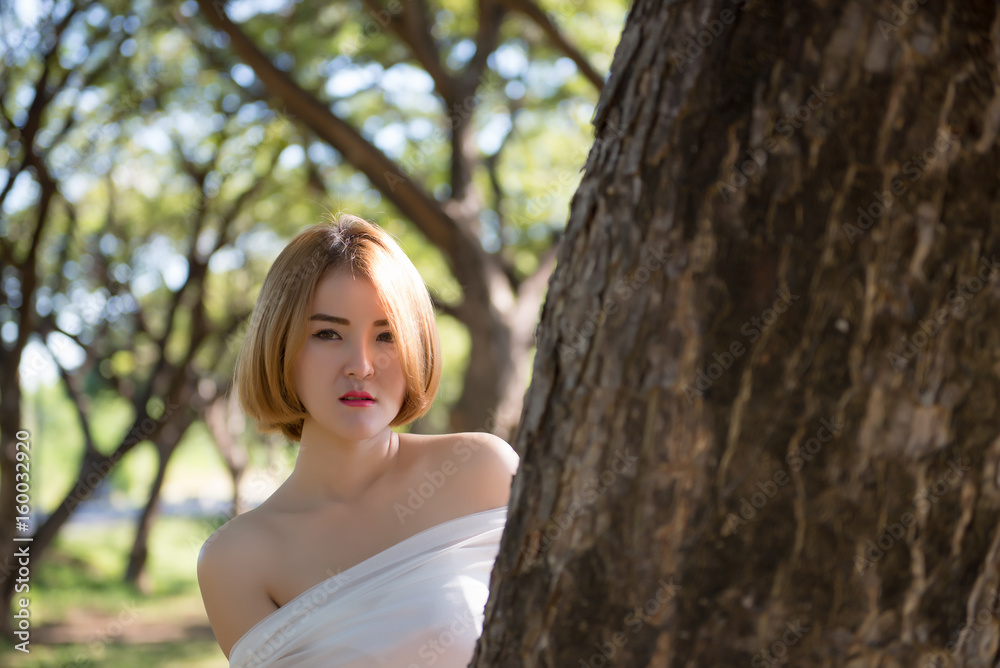 Beautiful woman smile stand under tree with bright sunlight,bright tone,sunny day Beautiful woman smile stand under tree with bright sunlight,bright tone,sunny day