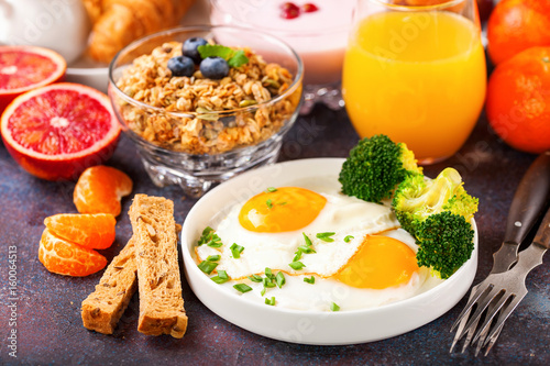 Breakfast - fried eggs with broccoli, muesli, croissant and juice on a table. Selective focus. Copy space