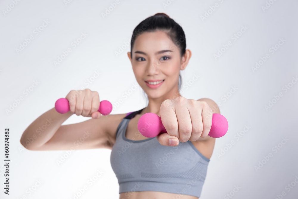 Young asian sporting woman training with dumbbell. Pretty athletic girl making physical exercise against white background. Healthy lifestyle concept. Young asian sporting woman training with dumbbell. Pretty athletic girl making physical exercise against white background. Healthy lifestyle concept.