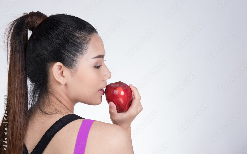 asian healthy athletic sporty girl with red apple after training. attractive smiling woman standing against white background. asian healthy athletic sporty girl with red apple after training. attractive smiling woman standing against white background.