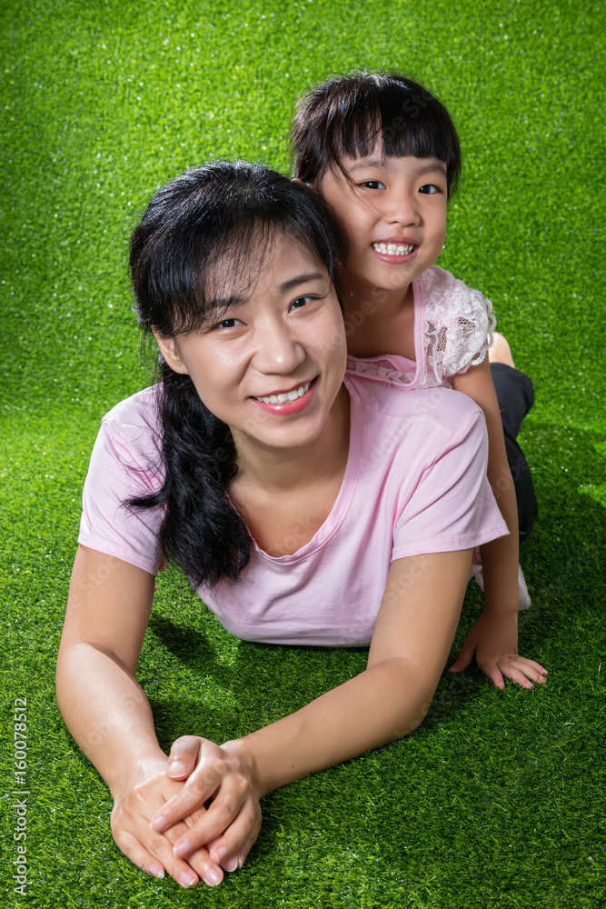 Asian Chinese little girl lying on her mother's back Asian Chinese little girl lying on her mother's back