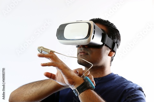 Young man wearing virtual reality goggles headset and heart monitor watch