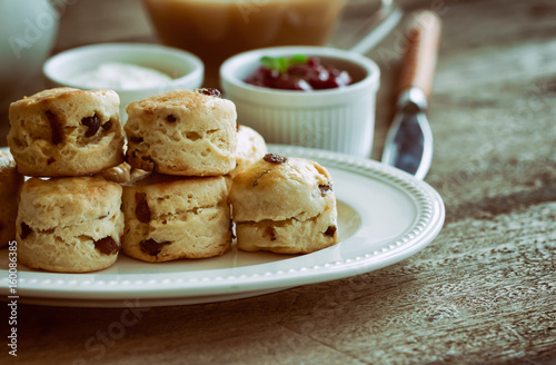Homemade raisin scones serve with homemade strawberries jam,clotted cream and tea.Scones is English pastry for afternoon tea,cream tea.Delicious scones Devon shire or Cornish cream style.