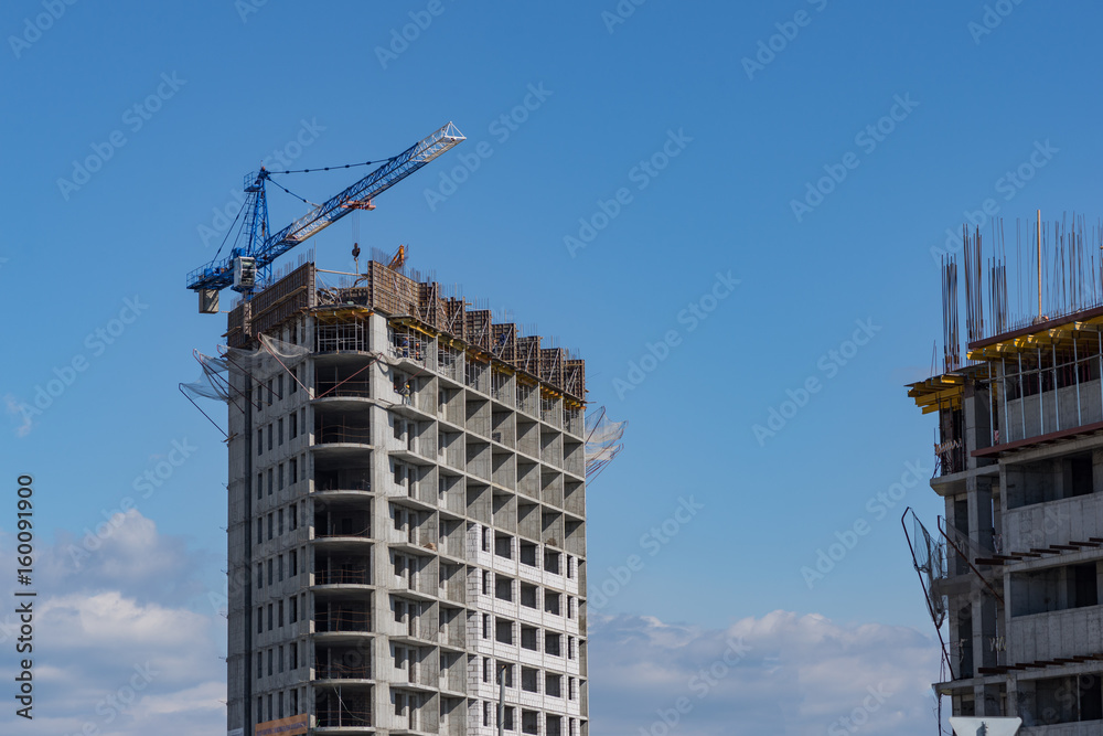 Construction of a house in the city. Cranes build a skyscraper