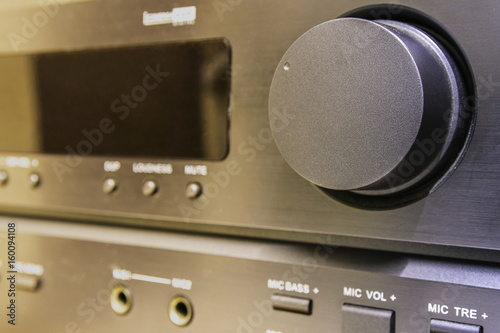 Close-up of a black audio amplifier, focusing on the control knobs and buttons, showcasing the sleek design and functionality of modern sound equipment.
