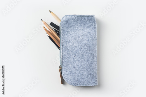 Fotografie Top view of grey fabric pencil case with lot of pens on white background desk fo