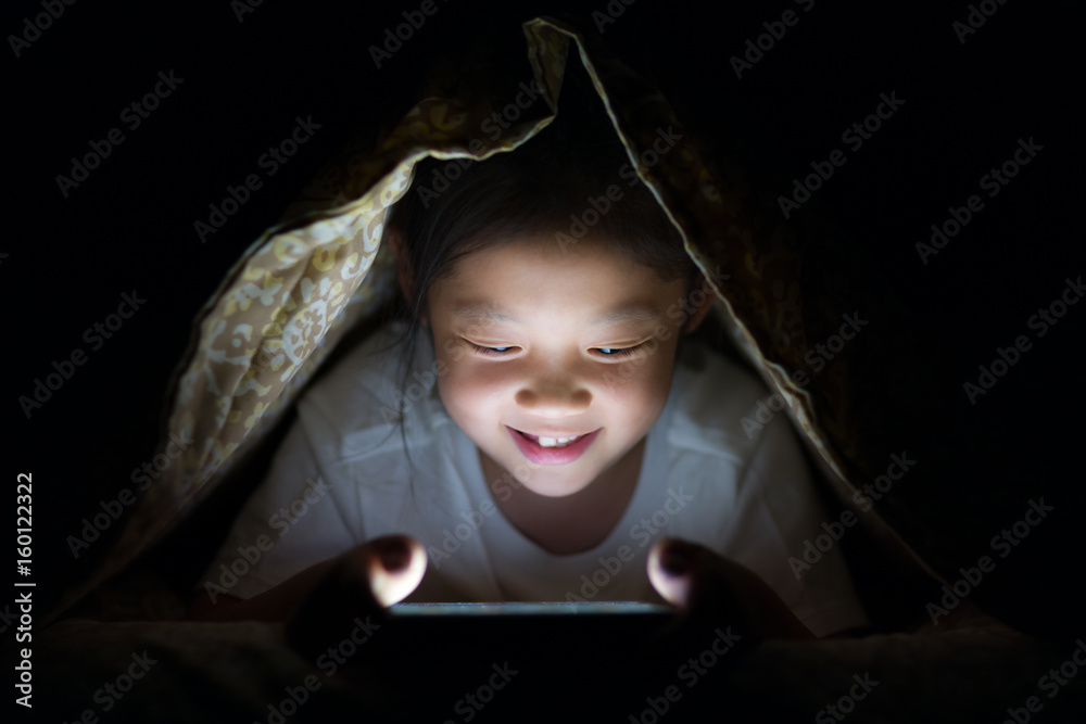 Asian Child Using Tablet PC in Bed at Night Asian Child Using Tablet PC in Bed at Night