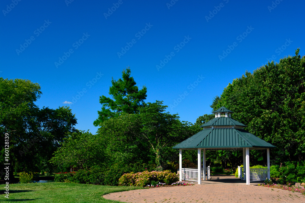A White Gazebo with Green Roof and Red Brick Patio in a Park on a Sunny