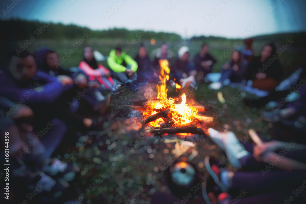 Friends are sitting around the bonfire - obrazy, fototapety, plakaty 