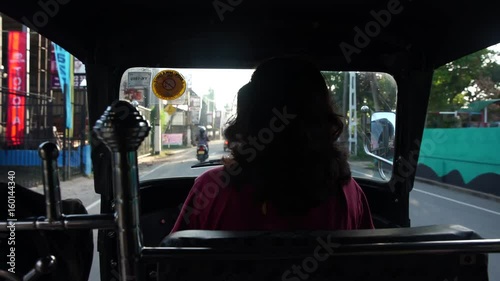 Female asian tuk-tuk driver with long hair riding at morning photo