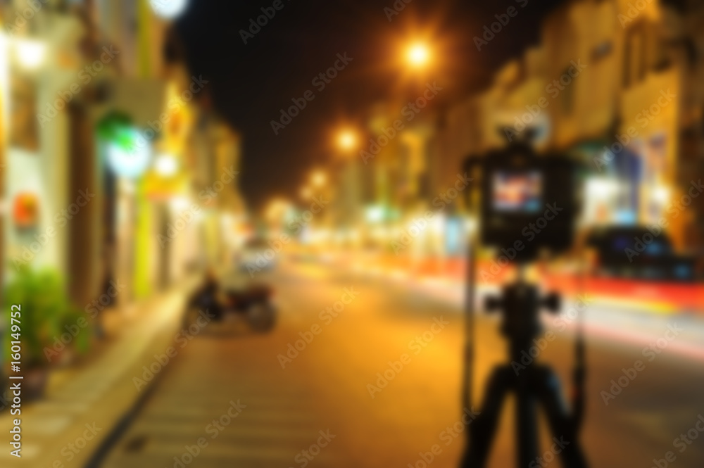 blurred camera on tripod in night street of city background