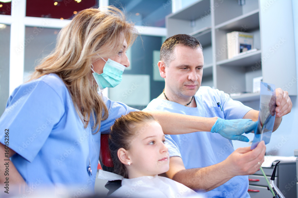 Professional female dentist with assistance of male doctor examining an