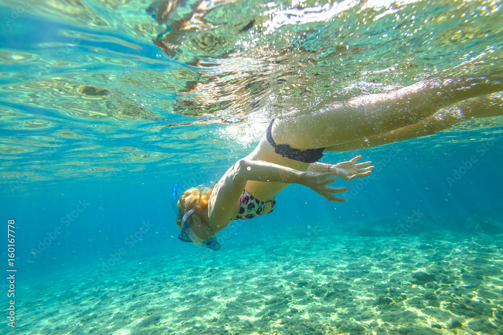 Female apnea bikini swims in crystal sea. Underwater background of a woman snorkeling and doing skin diving. Watersport activity in summer vacations. Tropical destination holidays concept.