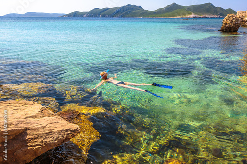Female bikini snorkeling around Methoni Castle, a medieval fortification in Methoni, Messenia, Peloponnese, Greece. Woman snorkeler swims in crystal water and roks. Nature scenic landscape.