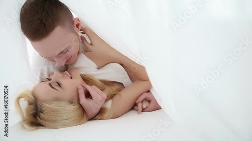 Happy young couple in love laying on the bed