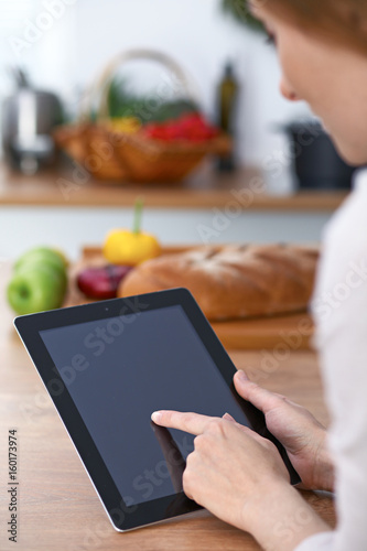 Close-up of human hands are gesticulate over a tablet in the kitchen. Women choosing menu or making online shopping. So much ideas for tasty cooking. Vegetarian, healthy meal and friendship concept