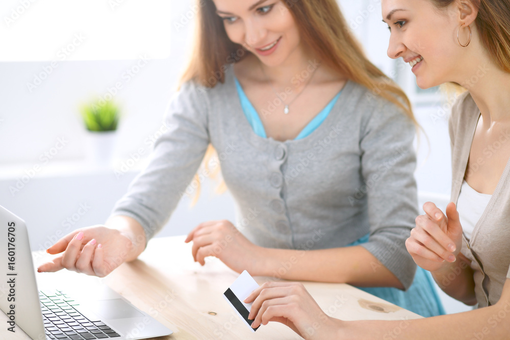 Two friends or sisters making online shopping by credit card. Friendship, family business or internet surfing concept Two friends or sisters making online shopping by credit card. Friendship, family business or internet surfing concept
