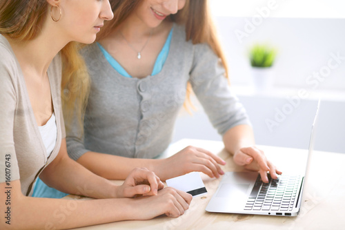 Two friends or sisters making online shopping by credit card. Friendship, family business or internet surfing concept