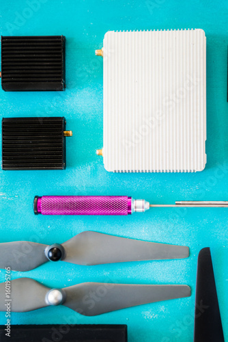 Top view of drone components, included propellers, video link, digital transmitter and screwdriver  on a rusty blue background wooden table photo