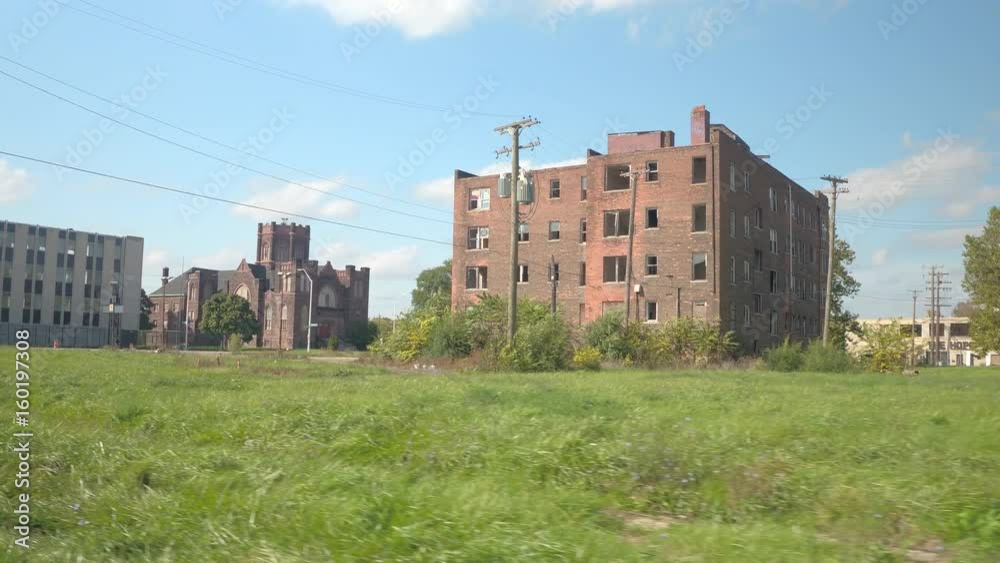 FPV Driving past huge brick-built residential building in ruins in decaying industrial zone of Detroit city, USA. Crumbling relict apartment block with broken windows near beautiful historic cathedral FPV Driving past huge brick-built residential building in ruins in decaying industrial zone of Detroit city, USA. Crumbling relict apartment block with broken windows near beautiful historic cathedral