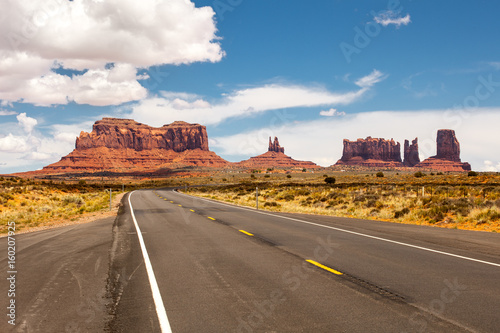 Road passing through Monument Valley, beautiful sunny day with blue sky in summer, Utah, USA