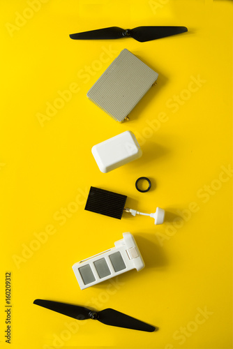 Top view of drone components, included propellers, video link, digital transmitter and screwdriver  on a yellow background photo