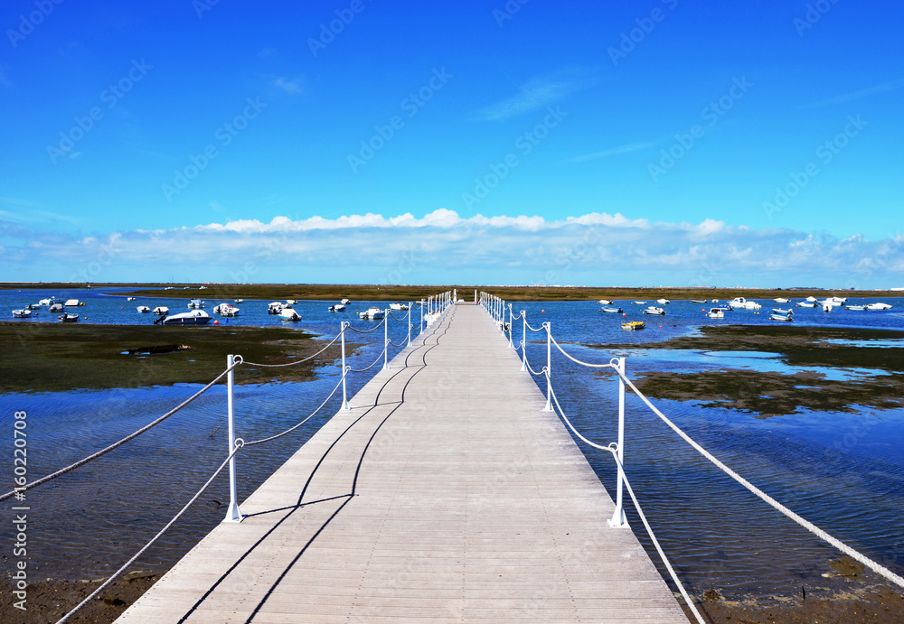 Wooden Harbour Jetty at Ria Formosa with blue sky in background  in Faro Marina, Algarve, Portugal