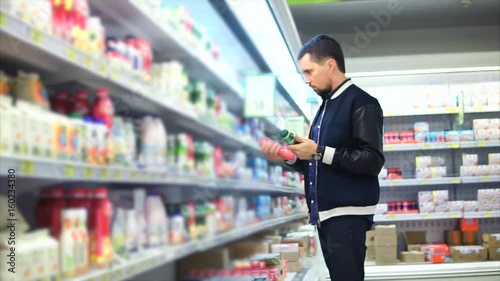 Wallpaper Mural An adult man chooses a package of milk in the dairy department of a grocery store, people see plastic cans with pasteurized milk for breakfast Torontodigital.ca