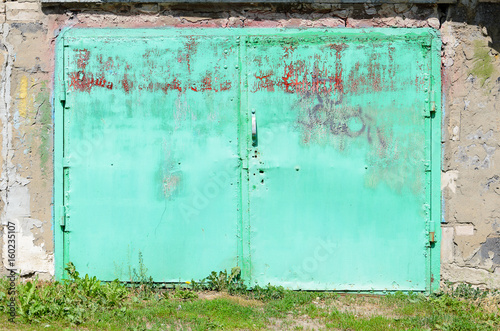 Garage facade with old green metal gates. Old garage door photo