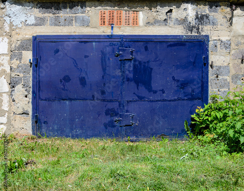 Garage facade with old dark blu gates. Old garage door photo