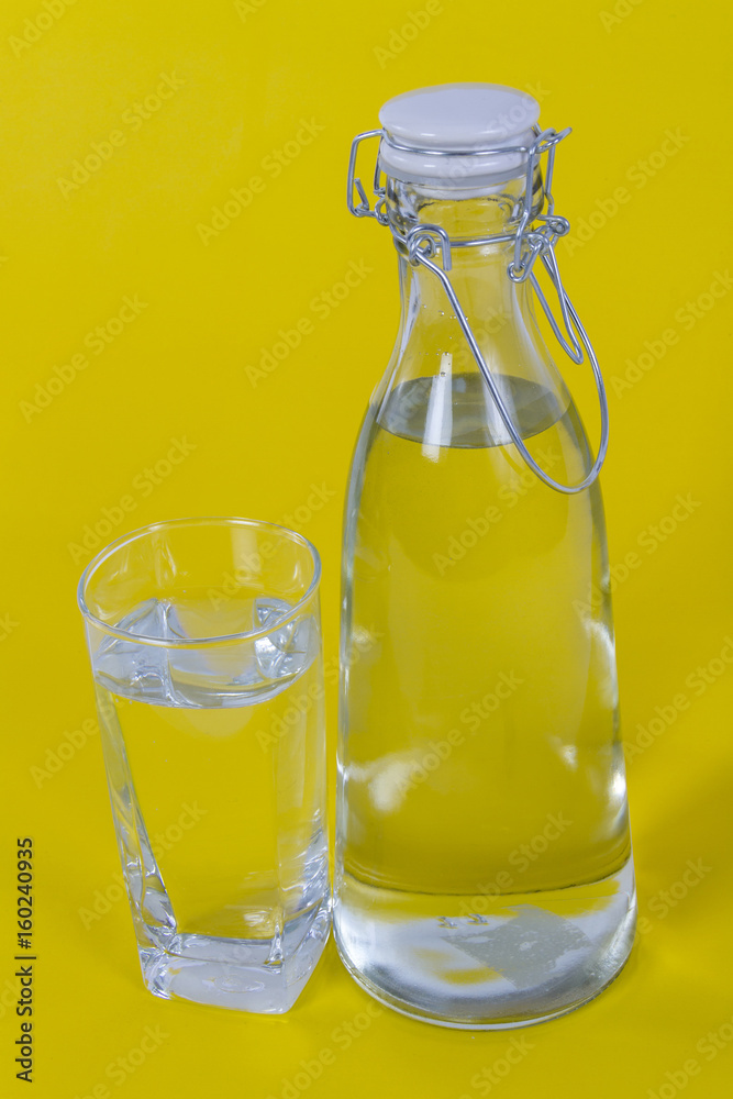 Bottled water and glass on yellow background Bottled water and glass on yellow background