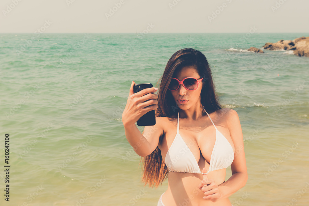 Beautiful attractive large breast asian bikini woman posing sexy portrait  on beach smart phone selfie Stock-Foto | Adobe Stock