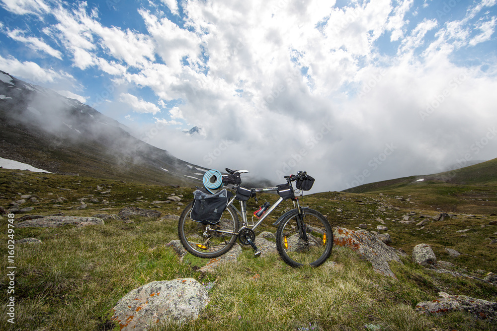 Bike traveler in the background of beautiful mountains with clouds