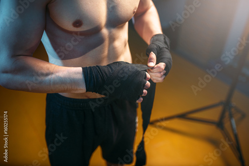 Fototapeta Muscular male person hands in black bandages